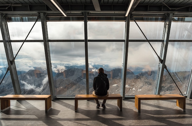 Un uomo seduto sul ponte di osservazione su una montagna Zugspitze