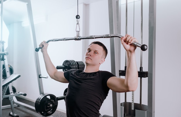 Un uomo si allena in palestra su un simulatore, fa esercizi per diversi gruppi muscolari. Voglie di petto, corpo atletico sano. moderno fitness club