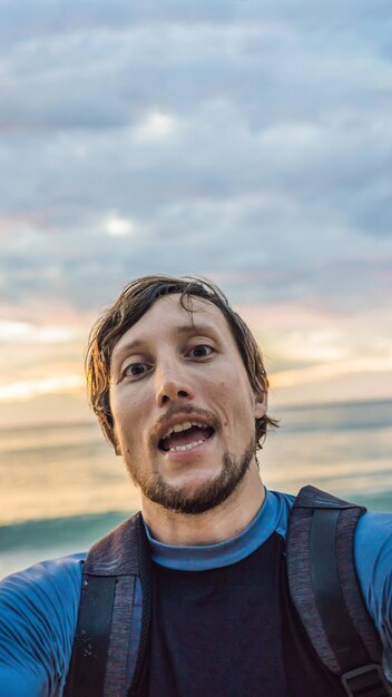 Un uomo si fa un selfie sullo sfondo del formato verticale del mare e del tramonto per instagram mobile