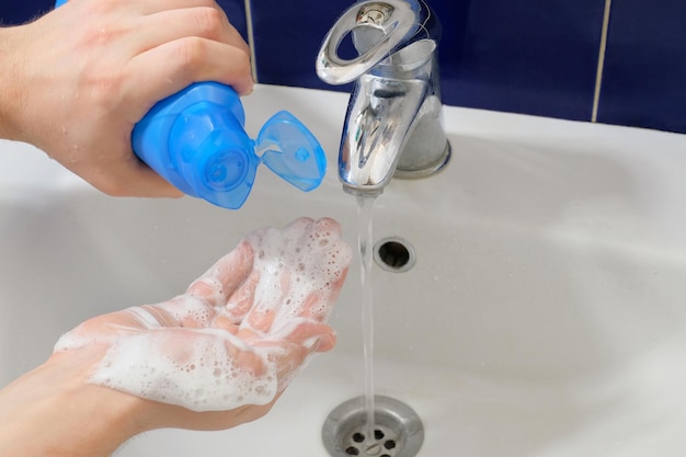 Un uomo si lava le mani con sapone liquido in bagno Concetto di igiene