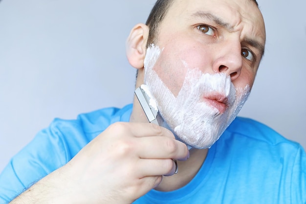 Un uomo si rade davanti a uno specchio Schiuma da barba Rasoio usa e getta