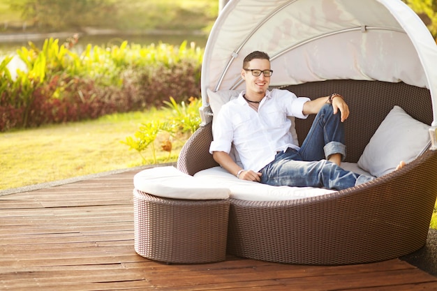 Un uomo si siede su un divano in un giardino