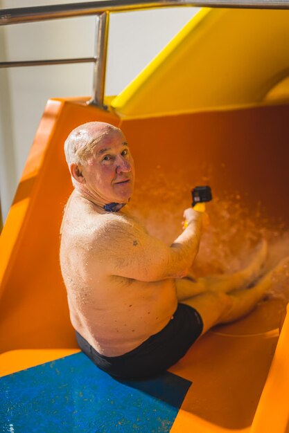 Un uomo si siede su uno scivolo d'acqua in una piscina con uno scivolo d'acqua giallo.