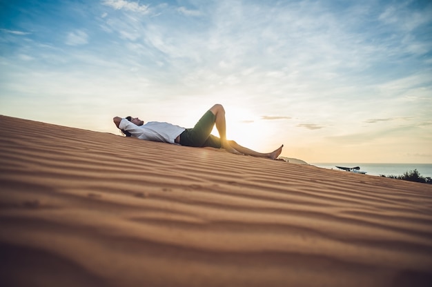 Un uomo si siede sulla sabbia nel deserto.