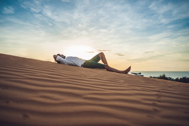 Un uomo si siede sulla sabbia nel deserto.