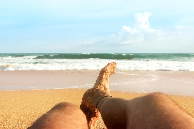 Un uomo si sta rilassando sulla spiaggia sabbiosa dello sfondo marino dell'Oceano Indiano