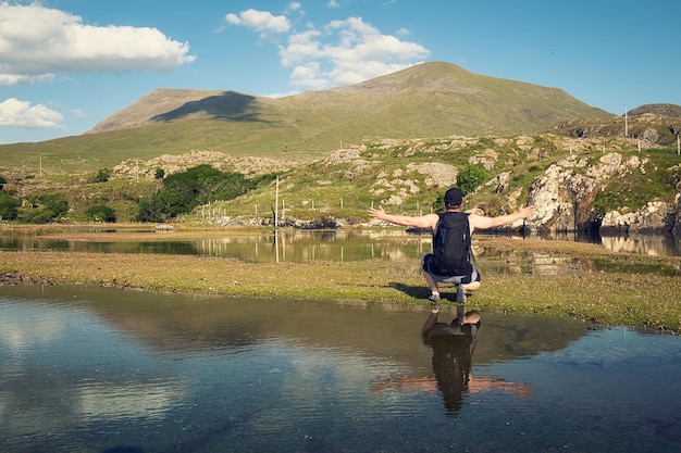 Un uomo si trova di fronte a un lago con le montagne sullo sfondo