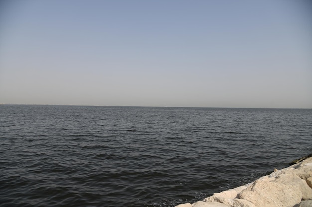 Un uomo si trova su una roccia di fronte a uno specchio d'acqua.