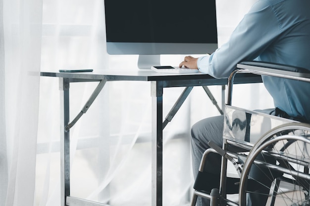 Un uomo siede su una sedia a rotelle un uomo disabile è su una sedia a rotelle e lavora nell'ufficio dell'azienda lavorando con il team aziendale e avendo una persona disabile come parte del team