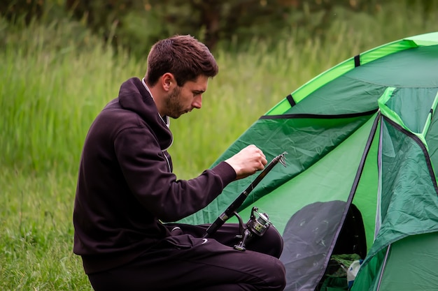 Un uomo siede vicino a una tenda turistica. Natura, svago, campeggio. Messa a fuoco selettiva