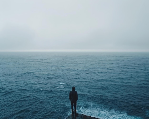 Un uomo solitario si trova sul bordo di una scogliera a fissare la vasta distesa dell'oceano
