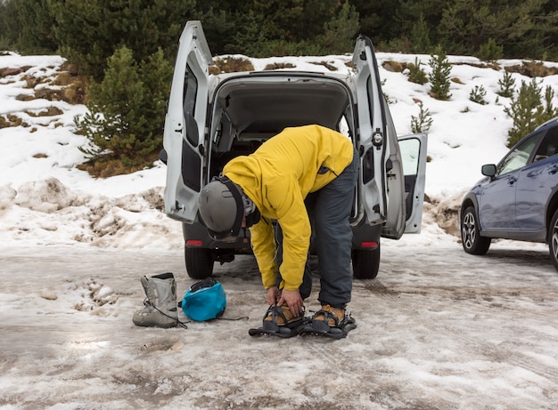 Un uomo sportivo che indossa le racchette da neve per iniziare un'escursione in montagna innevata.