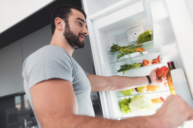 Un uomo sportivo prende le verdure dal frigo.