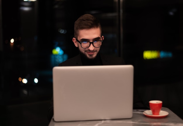 Un uomo sta lavorando su un laptop con una tazza di caffè sullo sfondo.