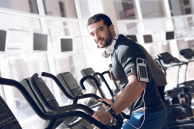 Un uomo sta praticando su un tapis roulant in una moderna palestra.