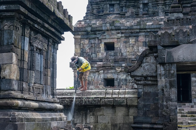 Un uomo sta pulendo le pareti del tempio spruzzando un fungicida