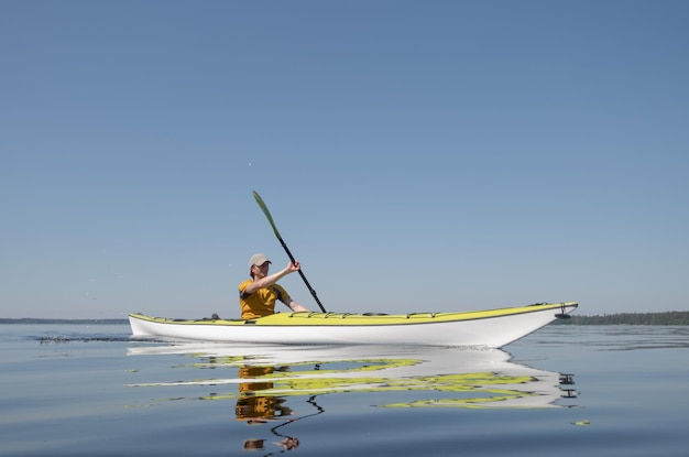 Un uomo su un kayak scivola sulla superficie dell'acqua