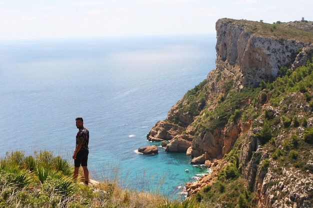 Un uomo su una scogliera di fronte al mare