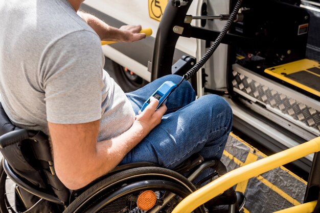 Un uomo su una sedia a rotelle su un ascensore di un veicolo per persone con disabilità.