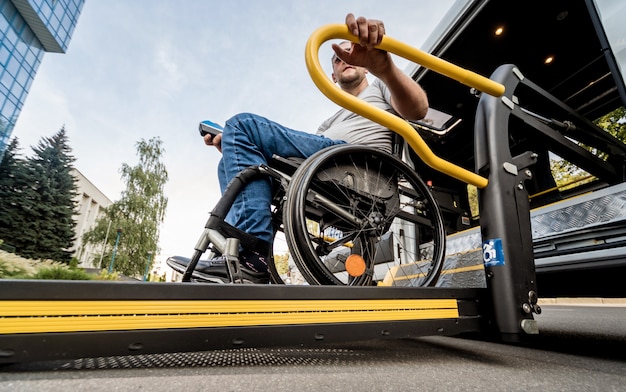 Un uomo su una sedia a rotelle su un ascensore di un veicolo per persone con disabilità.