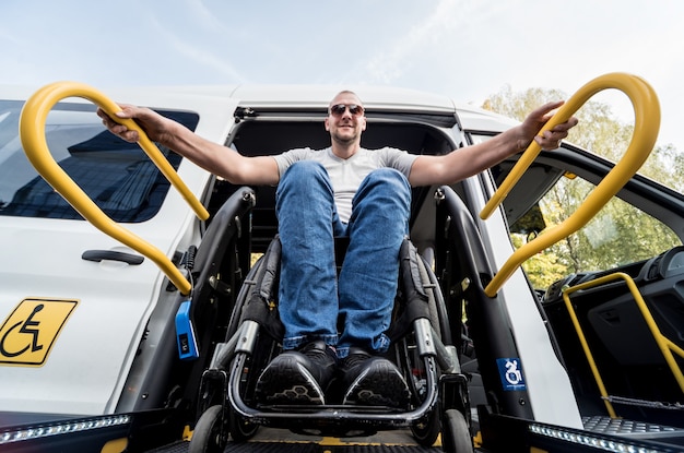 Un uomo su una sedia a rotelle su un ascensore di un veicolo per persone con disabilità.