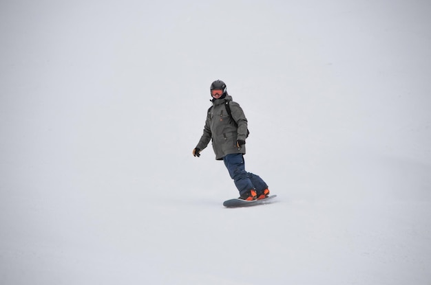 Un uomo su uno snowboard scende lungo il fianco della montagna