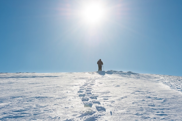 Un uomo sulla cima della montagna invernale con la neve