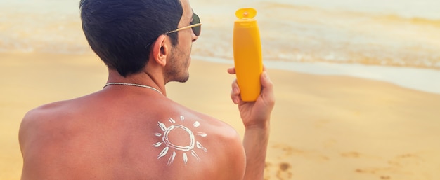 Un uomo sulla spiaggia con crema solare sulla schiena