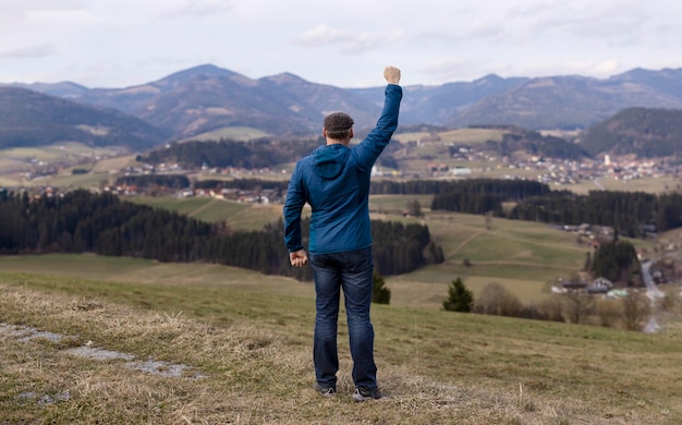 Un uomo sullo sfondo di un bellissimo paesaggio alpino agita la mano