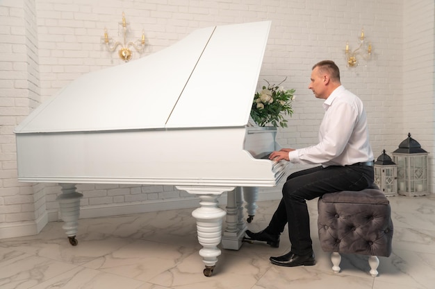 Un uomo suona il pianoforte in un interno bianco Il concetto di musica classica