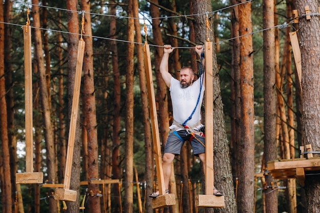 Un uomo supera un ostacolo in una città di corde Un uomo in un parco avventura nella foresta