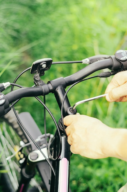 Un uomo svita i bulloni con una chiave esagonale sul manubrio di una mountain bike