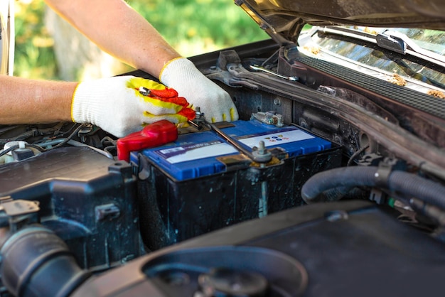 Un uomo svita il supporto della batteria dell'auto Riparazione e sostituzione della batteria