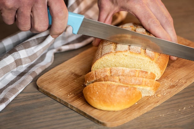 Un uomo taglia il pane con un coltello seghettato.