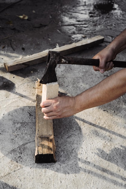 Un uomo taglia legna con un'ascia per accendere un fuoco Lavoro in cortile