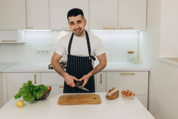 Un uomo taglia un avocado sul tavolo della cucina