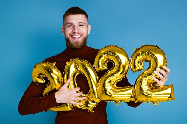 Un uomo tiene i numeri 2022 da palloncini dorati. Il nuovo anno in arrivo