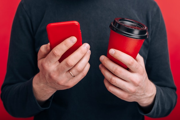 Un uomo tiene in mano un telefono e un bicchiere di carta