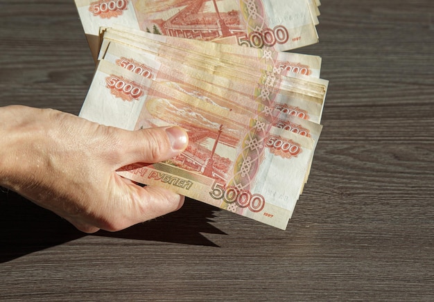 Un uomo tiene in mano un ventaglio di banconote da 5000 rubli in primo piano