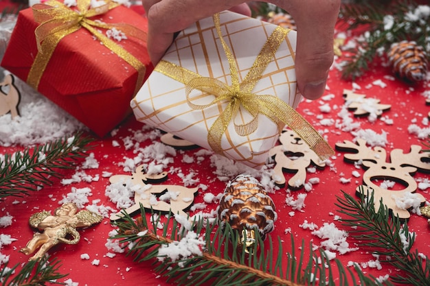 Un uomo tiene in mano una confezione regalo di Natale. Composizione di Natale. Bellissime scatole regalo di Natale.