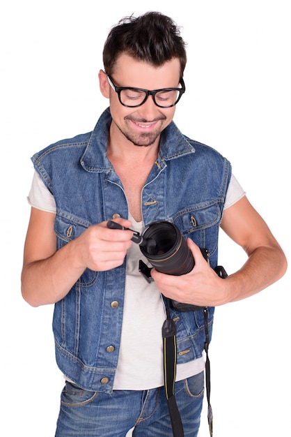 Un uomo tiene in mano una macchina fotografica e sorride.