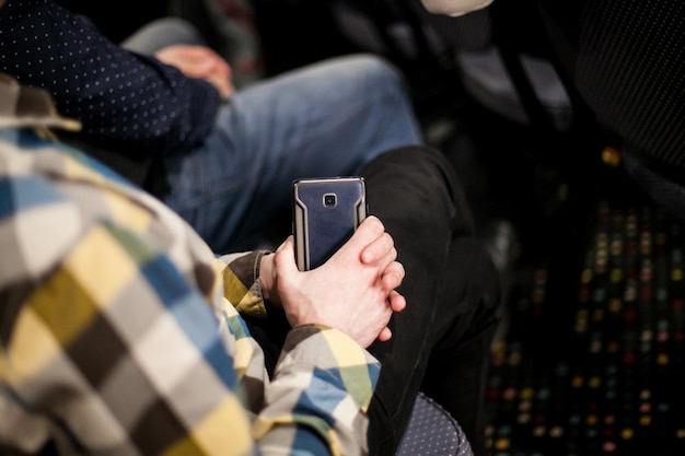 un uomo tiene in mano uno smartphone, primo piano delle mani con un telefono