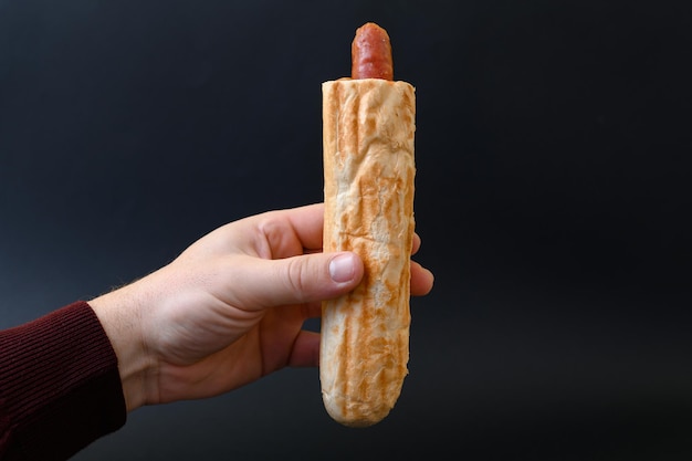 Un uomo tiene in mano uno spazio per copiare un hot dog francese e del cibo sullo sfondo