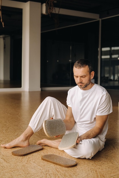 Un uomo tiene tra le mani tavole con chiodi per lezioni di yoga