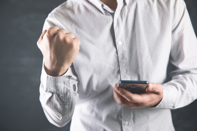 Un uomo tiene un telefono e mostra un buon segno