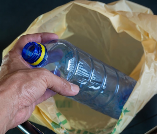 Un uomo tiene una bottiglia d'acqua in un sacchetto di carta.