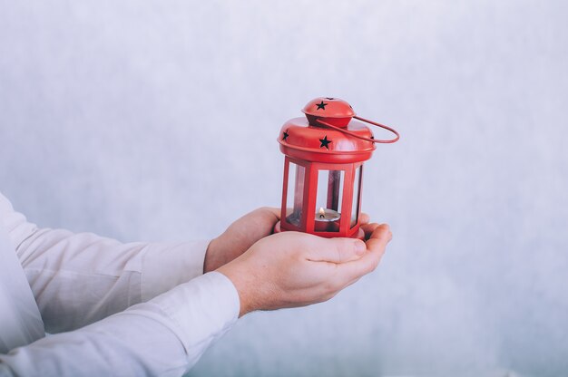 Un uomo tiene una lampada con una candela in mano su un bianco.