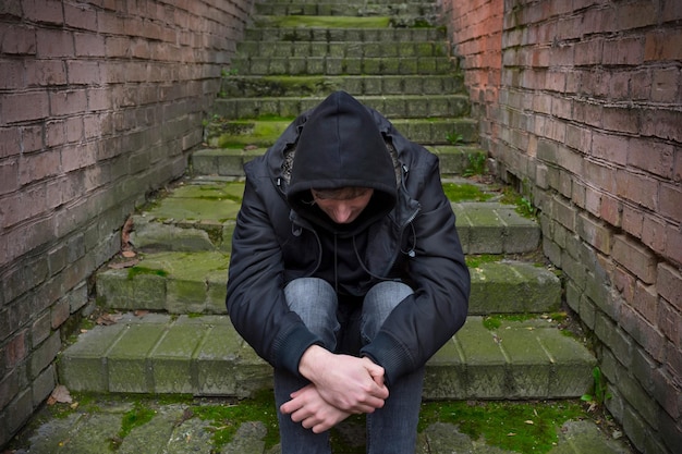 Un uomo tossicodipendente è seduto per strada vivendo una crisi di tossicodipendenza problemi sociali