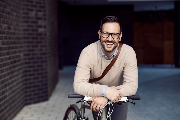 Un uomo urbano in posa con la bicicletta e sorridendo alla telecamera