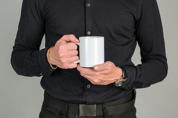 Un uomo vestito di nero tiene in mano una grande tazza di caffè bianca